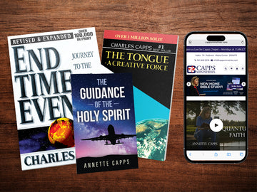 Four books on a wooden surface with a phone displaying a website. CappsMinistries.om