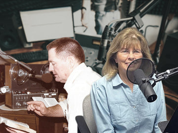 Two people in a radio studio with Charles Capps reading from a book and Annette Capps sitting next to a microphone.